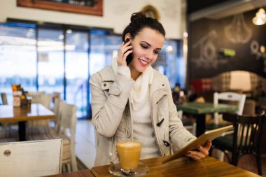 Kafede dijital tablet kullanarak çekici genç kadın