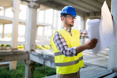 Mühendis bir mavi parmak tutan bir şantiyeye çalışıyor