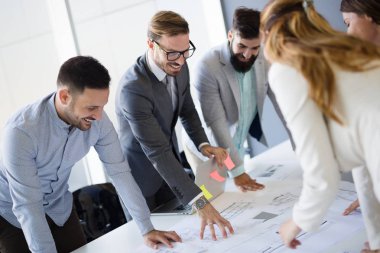 Takım inşaat planları üzerinde birlikte çalışan mimarlar