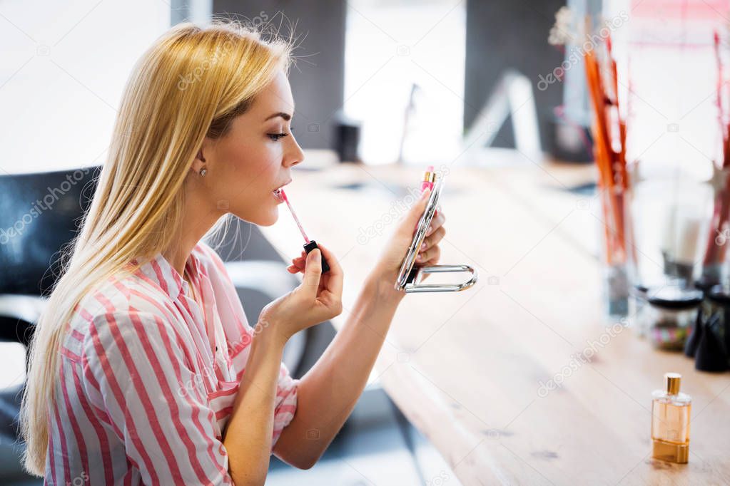 Beautiful woman paints lips with lipstick. Beautiful woman face