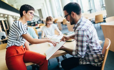 Genç çekici öğrenci üniversite kitaplığında vakit