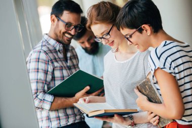 Grup genç öğrenci üniversite kitaplığında tartışıyor