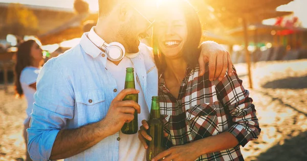 Lyckliga paret leende och druckit öl på stranden — Stockfoto