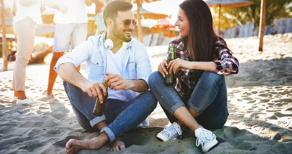 Счастливая пара улыбается и пьет пиво на пляже — стоковое фото