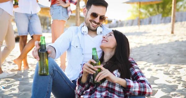 幸せなカップルの笑顔やビーチでビールを飲む — ストック写真