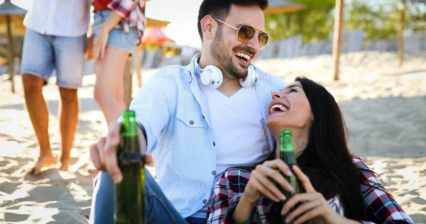 Usmíval se šťastný pár a popíjeli pivo na pláži — Stock fotografie