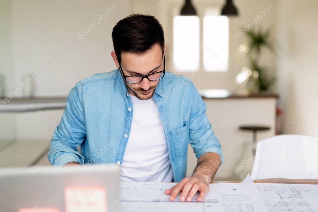 Architect working on plans at home office table and drawing