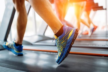 Spor salonunda koşu bandında kardiyo antrenmanı yapan insanların fotoğrafı.