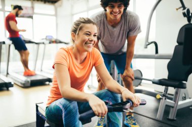 Genç ve güzel bir kadın spor salonunda antrenörle egzersiz yapıyor.