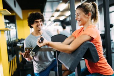Genç ve güzel bir kadın spor salonunda antrenörle egzersiz yapıyor.