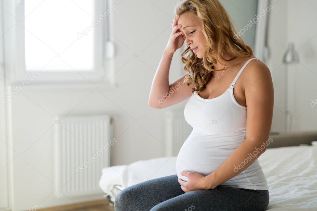 Portrait of pregnant blonde woman suffering from headache