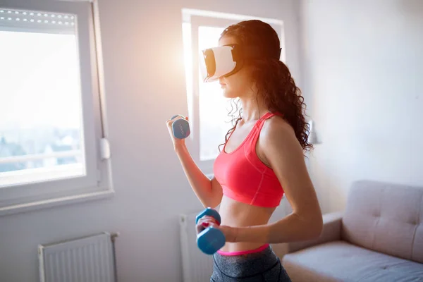 Young fitness woman doing exercises wearing vr goggles