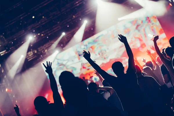 Cheering crowd with hands in air enjoying at music festival