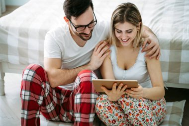 Genç mutlu çift yatak odasında dijital tablet kullanma