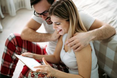 Genç mutlu çift yatak odasında dijital tablet kullanma