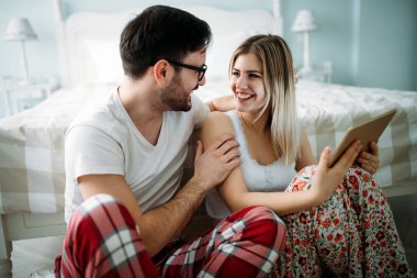 Genç mutlu çift yatak odasında dijital tablet kullanma