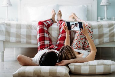 Genç mutlu çift yatak odasında dijital tablet kullanma