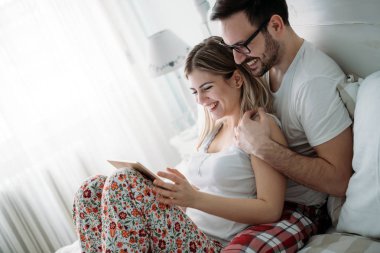 Genç mutlu çift yatak odasında dijital tablet kullanma
