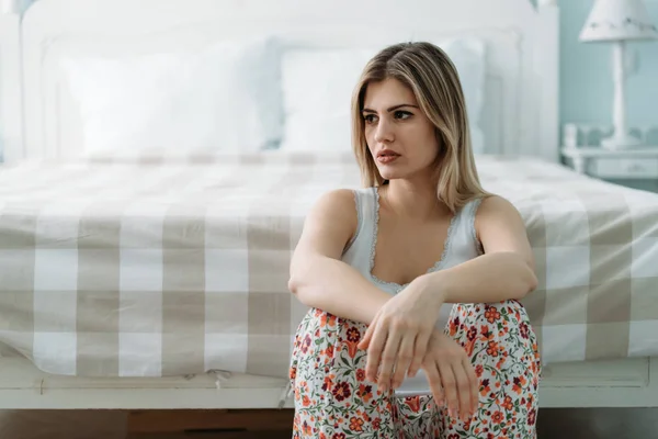 沮丧的年轻妇女坐在床上独自在家 — 图库照片