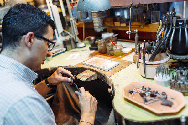 Goldsmith working on his bench, crafting jewelry