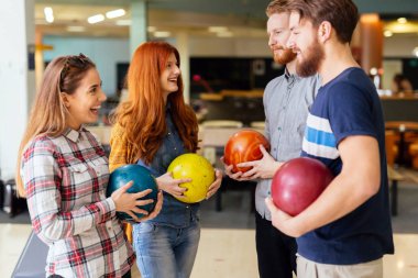 Happy friends having fun and enjoying playing bowling together clipart