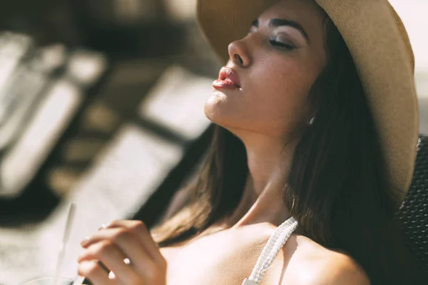 彼女のカクテルを飲んで 帽子と白いビキニを着て日光浴の見事な美しさ — ストック写真