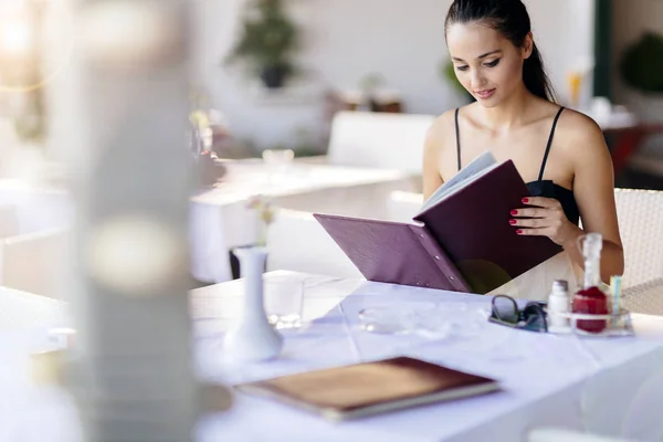 Beautiful woman ordering from menu in restaurant