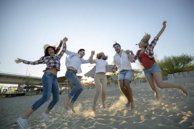 Mutlu bir grup genç insan yaz aylarında kumsalda eğleniyor