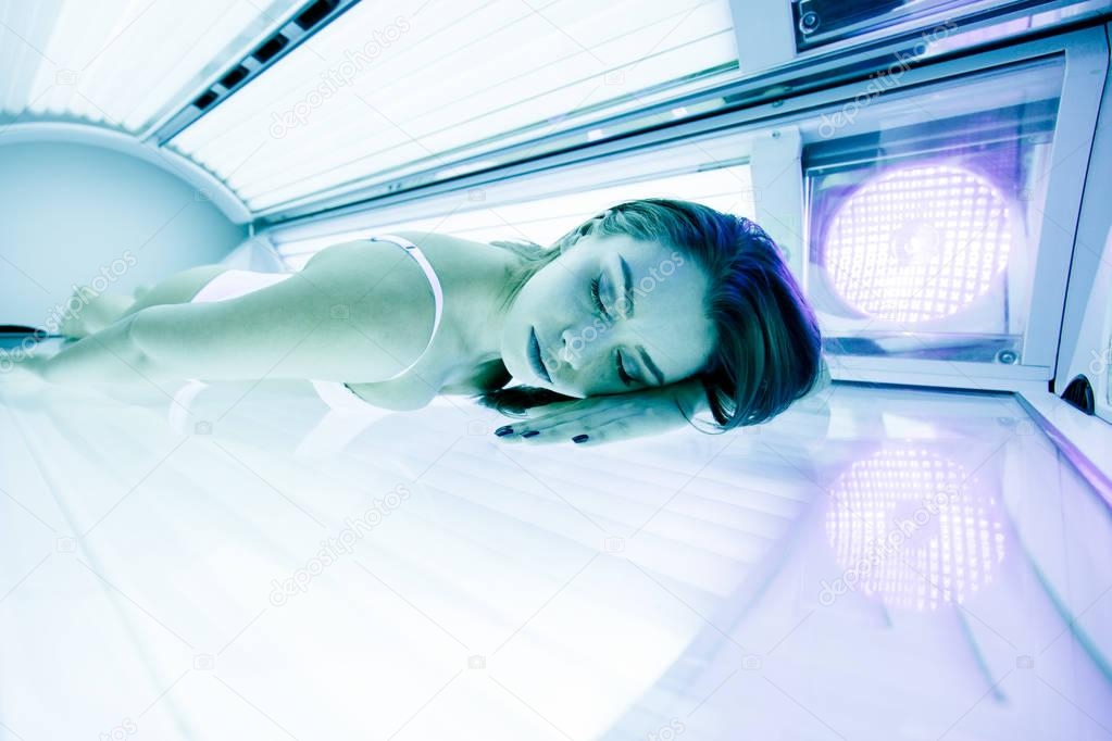 Beautiful woman lying in solarium and sunbathing