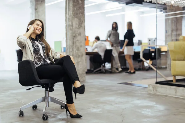 Confident business woman using phone in an office