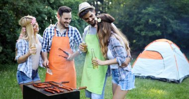Neşeli arkadaşlar doğada vakit geçirip barbekü yapıyorlar.