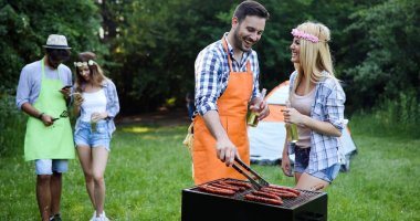 Neşeli arkadaşlar doğada vakit geçirip barbekü yapıyorlar.