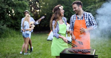 Neşeli arkadaşlar doğada vakit geçirip barbekü yapıyorlar.