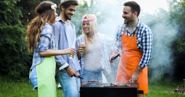 Neşeli arkadaşlar doğada vakit geçirip barbekü yapıyorlar.