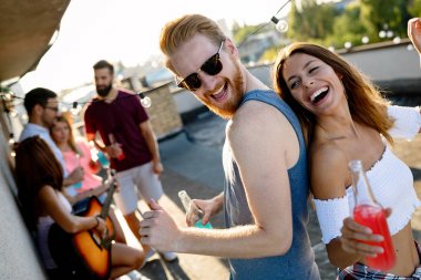 Bir grup mutlu genç arkadaş çatıda parti veriyor.