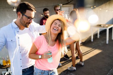 Bir grup mutlu genç arkadaş çatıda parti veriyor.