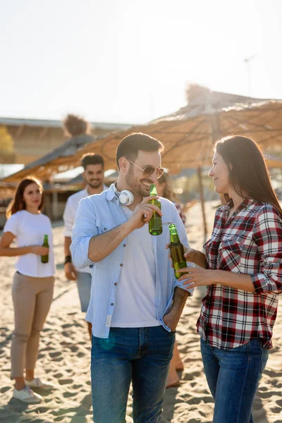 笑いとビーチでビールを飲む若い友人のグループ — ストック写真