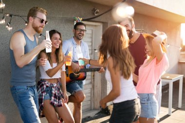 Bir grup mutlu genç arkadaş çatıda parti veriyor.