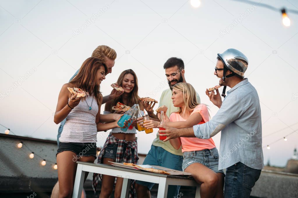 Group of young people sitting around and eating pizza. Friends partying and eating pizza.