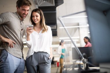 Ofiste iş arkadaşlarıyla birlikte çalışan ve iletişim kuran bir grup iş adamı.