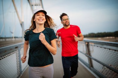 Spor çifti. Genç adam ve kadın dışarıda koşuyorlar.