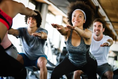 Bir spor salonunda antrenman yapan bir grup insan. Antrenör ve sportif fit insanlar bir fitness sınıfında egzersiz yapıyor