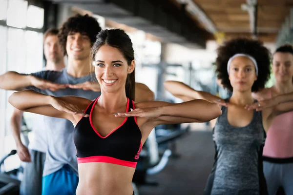 Bir spor salonunda antrenman yapan bir grup insan. Antrenör ve sportif fit insanlar bir fitness sınıfında egzersiz yapıyor