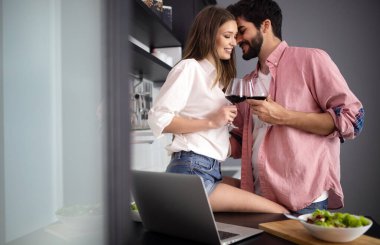 Mutlu çift modern mutfakta Kahvaltı yaparken dizüstü bilgisayar kullanarak