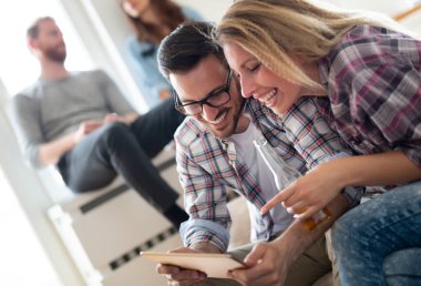 Dijital tablet oynayan ve bakan genç mutlu arkadaşlar