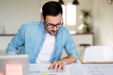 Ofiste çizim tablosu üzerinde çalışan genç mimar