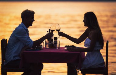 Tropikal tatil akşam yemeği sırasında tost genç romantik çift
