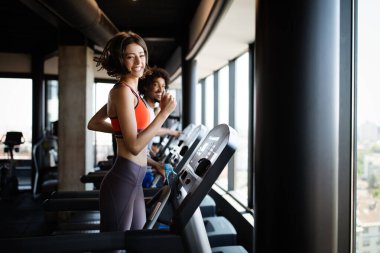 Spor salonunda koşu bandında egzersiz yapan bir grup genç arkadaş.