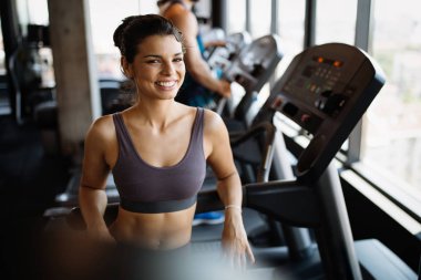 Spor salonunda koşu bandında egzersiz yapan bir grup genç arkadaş.