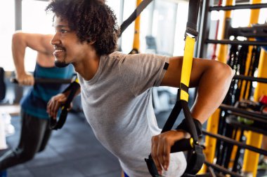 Spor salonunda trx fitness kayışlarıyla şınav çeken bir adam. Sağlıklı yaşam tarzı spor konsepti